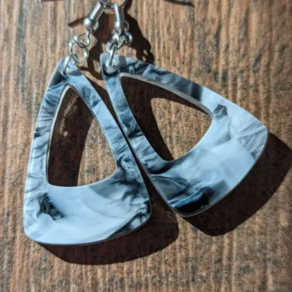 Triangular shaped black marble dangle earrings against a wooden backdrop