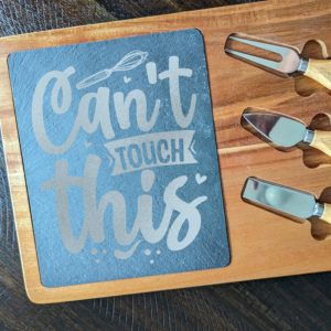 Wooden cheese board set with slate insert engraved with 'Can't touch this' and three cheese knives with wooden handles.