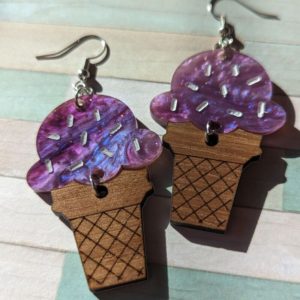 Fun and colorful ice cream cone earrings with sparkly purple tops, photographed on a pastel striped background.