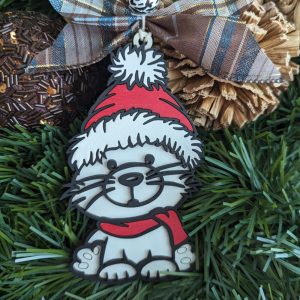 Single wooden Christmas cat ornament wearing a Santa hat and red scarf, shown on green grass with decorative accents and a plaid ribbon.