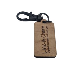 Rectangular wooden keychain with black metal clasp engraved with 'Link-A-Charm – Digital Content in Every One'